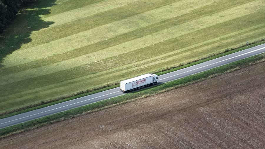 A truck driving on a road through farmland